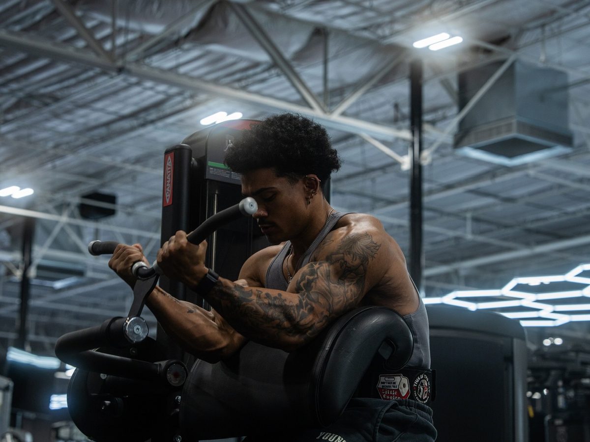 Member training on a plate-loaded machine at House of Gainz